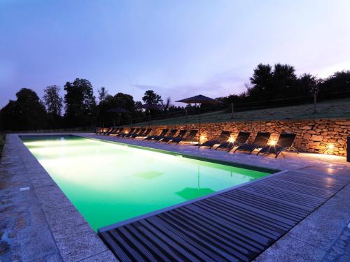 a swimming pool with chairs around it at night at Abbaye du Palais in Thauron