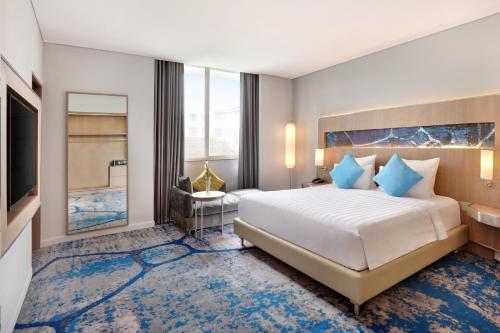 a hotel room with a bed and a television at Novotel Jakarta Mangga Dua Square in Jakarta