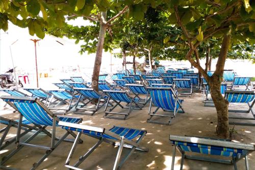 a bunch of chairs sitting under trees on the beach at Nhi Lo Home Stay in Tân Hiệp