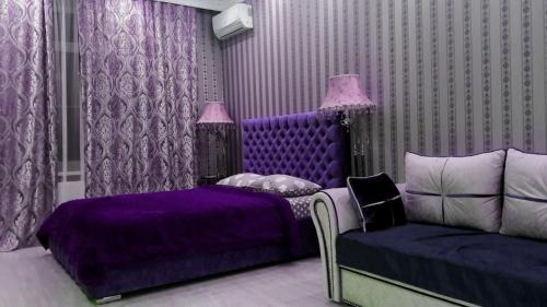 ウラジカフカスにあるVip Kvartira V Stile Loftの紫色のベッドルーム(ベッド1台、ソファ付)