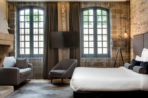 a hotel room with a bed and a chair at Boutique Hôtel des Remparts & Spa in Aigues-Mortes