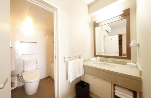 a bathroom with a toilet and a sink and a mirror at Vessel Hotel Campana Okinawa in Chatan