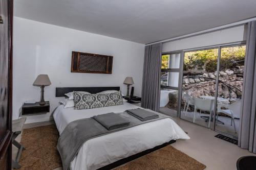a bedroom with a bed and a balcony with a tub at Agulhas Ocean House in Agulhas