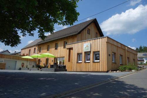 duży drewniany budynek z parasolem przed nim w obiekcie Speedys Gästehaus w mieście Baar