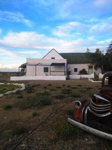 a white house with a truck in front of it at Silwerkaroo Gastehuis in Beaufort West