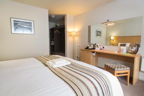 a bedroom with a bed with a desk and a mirror at Best Western The Dartmouth Hotel, Golf & Spa in Dartmouth