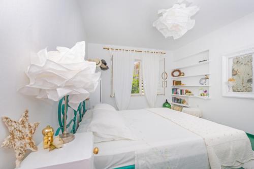 a white bedroom with a bed and a flower on a table at Apartment and Rooms Lapad in Dubrovnik