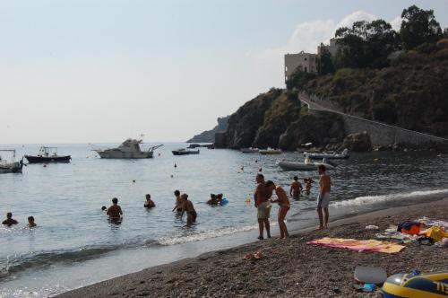 un groupe de personnes dans l'eau d'une plage dans l'établissement Residence Hotel Baia Portinenti, à Lipari