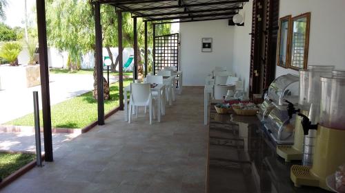 een kamer met witte stoelen, een tafel en ramen bij I Tre Ciliegi in Otranto