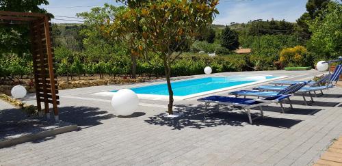 a pool with lounge chairs and a tree next to it at Bed House Floristella in Valguarnera Caropepe