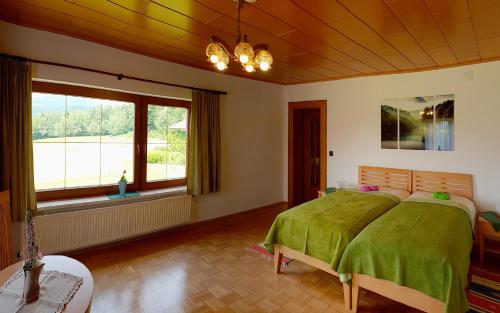 a bedroom with a green bed and a large window at Bungalow & Apartments "Am Deber" Velden - Augsdorf in Velden am Wörthersee