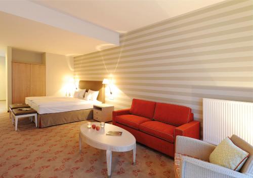 バート・ノイェンアール・アールヴァイラーにあるLandhotel Sanct Peterのベッドと赤いソファが備わるホテルルームです。