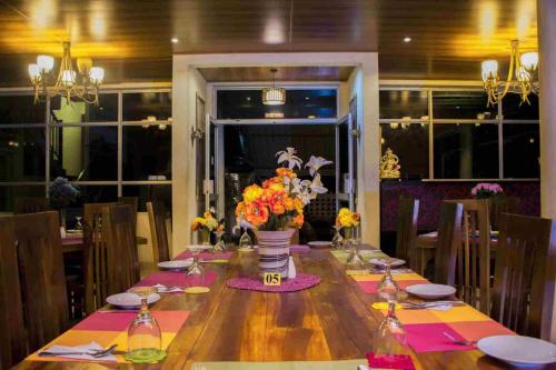a wooden table with a vase of flowers on it at Hill Cool Hotel & Restaurant in Hatton