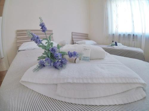twee bedden met witte dekens en paarse bloemen erop bij Casa Claudia in La Spezia