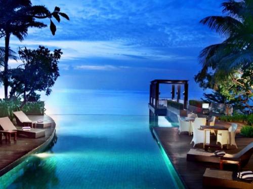 a pool with a view of the ocean at night at The Malibu Suites Balikpapan by Sissae Living in Balikpapan