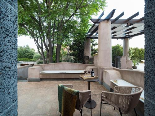 a patio with a table and chairs and a bench at Relais San Giuliano in Viagrande
