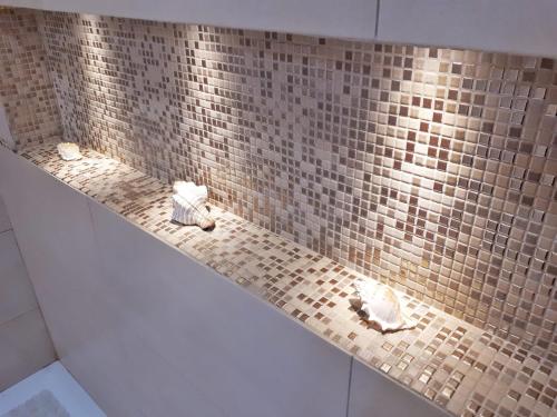 een douche met twee rotsen op een betegelde muur bij Casa Claudia in La Spezia