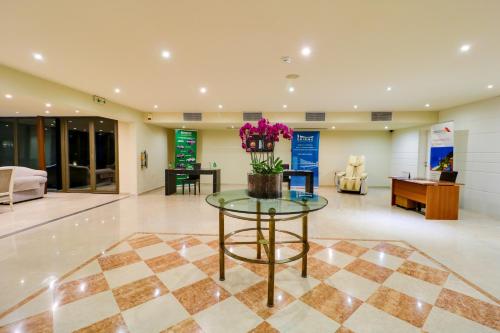 a lobby with a glass table with flowers on it at Olympian Bay Grand Resort in Leptokarya