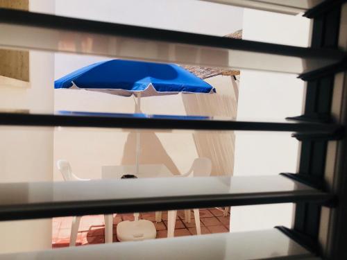 a table with a blue umbrella and chairs at Casa Vacanze Sonetto in Maruggio