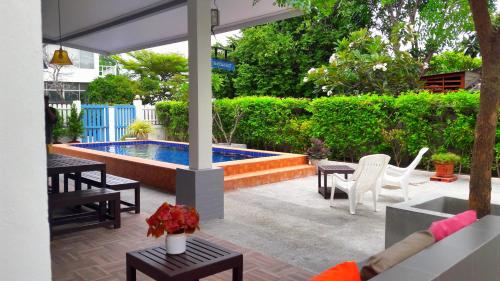 patio z basenem, stołami i krzesłami w obiekcie Baan Pare w mieście Pran Buri