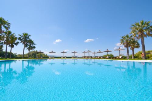 une grande piscine avec des palmiers en arrière-plan dans l'établissement Fairplay Golf & Spa Resort, à Benalup-Casas Viejas