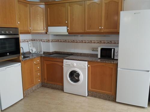a kitchen with a washing machine and a refrigerator at Calle Miguel Delibes in San Bartolomé