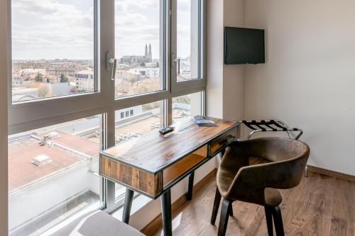 a desk and a chair in a room with windows at All Suites Appart Hôtel - Bordeaux Centre Gare in Bordeaux