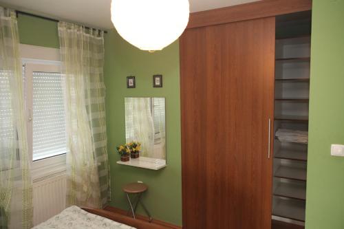 a bedroom with green walls and a door with a mirror at Dalma in Osijek