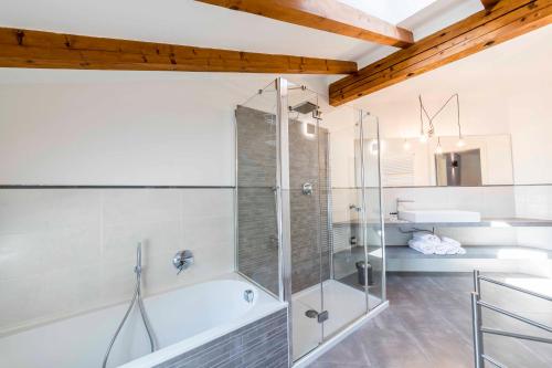 a bathroom with a tub and a glass shower at Stay COOPER l Goethe Suite in Bolzano