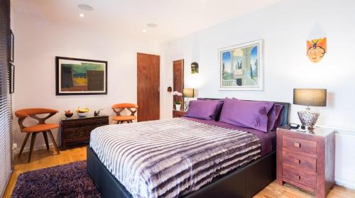 1 dormitorio con 1 cama grande con almohadas moradas en Romantic Bungalow in Notting Hill, en Londres