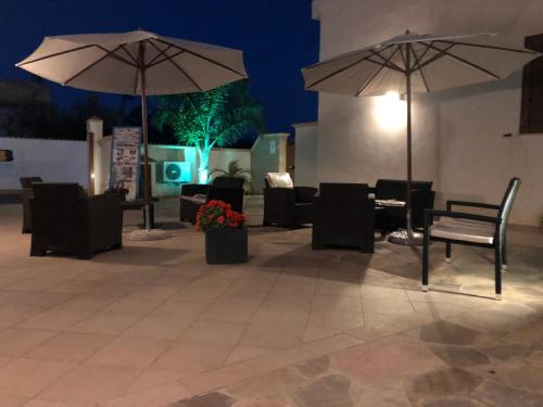 two umbrellas sitting on a patio with tables and chairs at Bono Vacanze Villa San Marco Luxury Holidays Homes in Sciacca