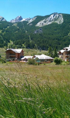 a field of grass with houses and mountains in the background at Chalet Apartment Monêtier in Le Monêtier-les-Bains