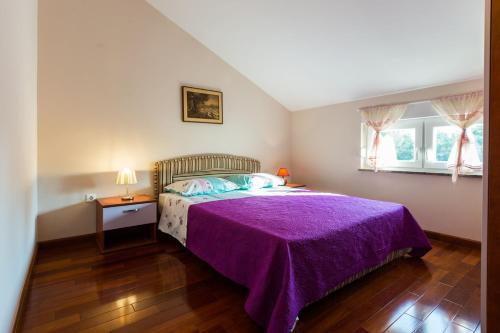 sypialnia z fioletowym łóżkiem i oknem w obiekcie Apartments Villa Orion w mieście Kožino