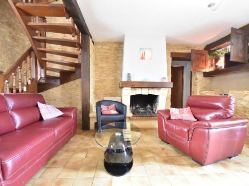 a living room with red leather couches and a fireplace at Modern holiday home in Besse with private pool in Villefranche-du-Périgord
