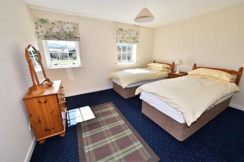 a bedroom with two beds and a table and two windows at Knocklea in Alness