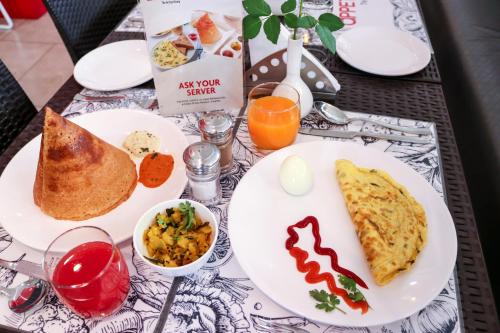 a table with plates of breakfast food on it at 7 Apple Hotel, Vadodara in Vadodara
