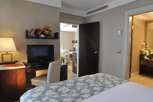 a hotel room with a bed and a desk and a television at Ramada Plaza Antalya in Antalya