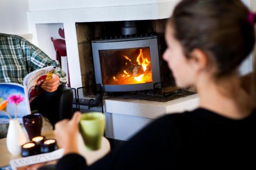 eine Frau, die an einem Tisch vor einem Kamin sitzt in der Unterkunft Långbergets Sporthotell in Sysslebäck