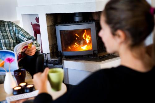 a woman sitting at a table in front of a fireplace at Långbergets Sporthotell in Sysslebäck