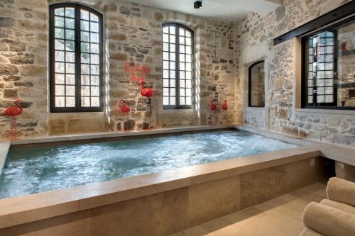 a hot tub in a room with a stone wall at Boutique Hôtel des Remparts & Spa in Aigues-Mortes