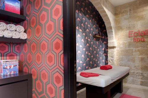 a room with a bed with red pillows on it at Boutique Hôtel des Remparts & Spa in Aigues-Mortes