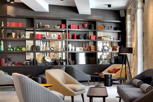 a lobby with couches and chairs and shelves at Boutique Hôtel des Remparts & Spa in Aigues-Mortes