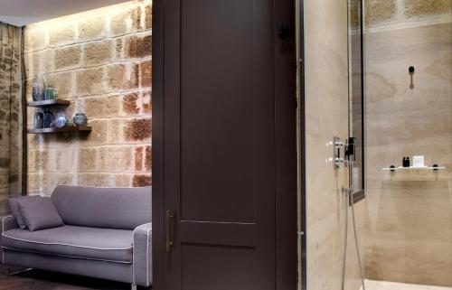 a room with a chair and a glass door at Boutique Hôtel des Remparts & Spa in Aigues-Mortes