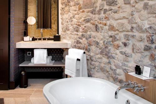 a bathroom with a bath tub and a stone wall at Boutique Hôtel des Remparts & Spa in Aigues-Mortes
