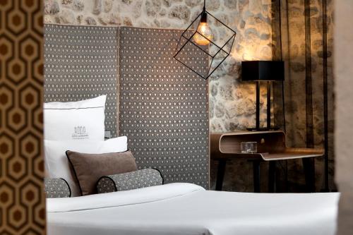 a bedroom with a bed and a chair and a desk at Boutique Hôtel des Remparts & Spa in Aigues-Mortes