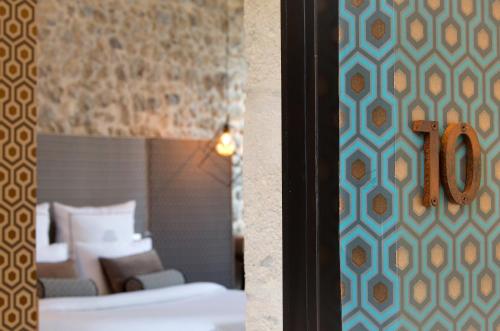 a hotel room with two beds and a number on a wall at Boutique Hôtel des Remparts & Spa in Aigues-Mortes