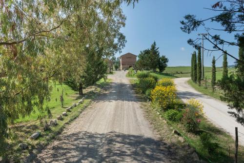a dirt road with a house in the distance at Wine Resort Colsereno in Montalcino