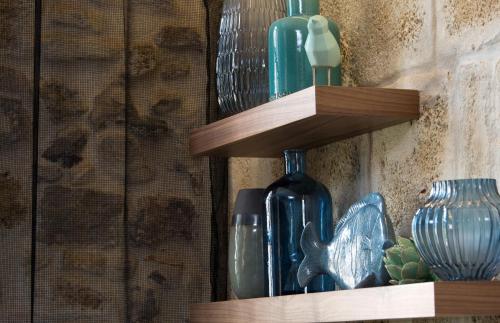 a group of glass bottles and vases on wooden shelves at Boutique Hôtel des Remparts & Spa in Aigues-Mortes