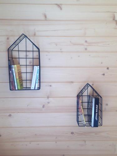 deux cages d'oiseaux suspendues sur un mur avec des livres dans l'établissement Domki Między Sosnami, à Pobierowo