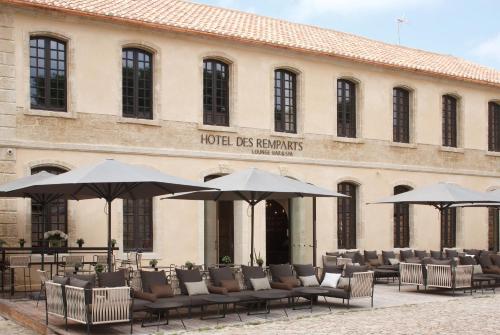 a building with chairs and umbrellas in front of a building at Boutique Hôtel des Remparts & Spa in Aigues-Mortes